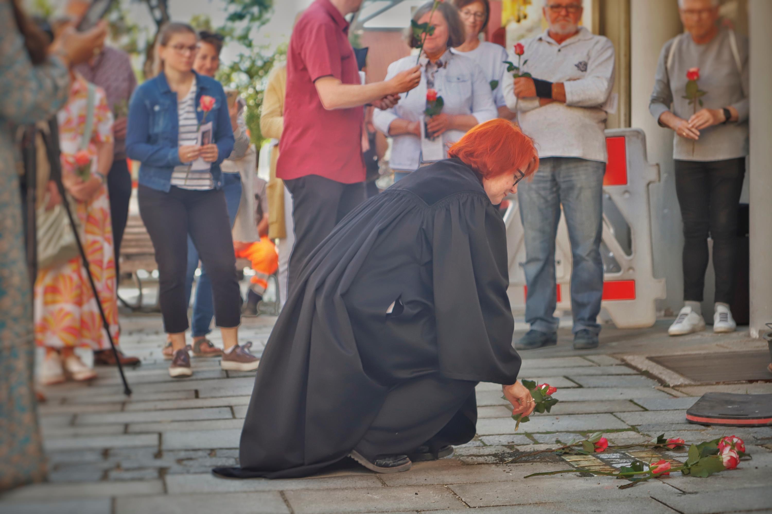 Auch Dekanin Christiane Murner legt bei den Stolpersteinen eine Rose für die Opfer nieder